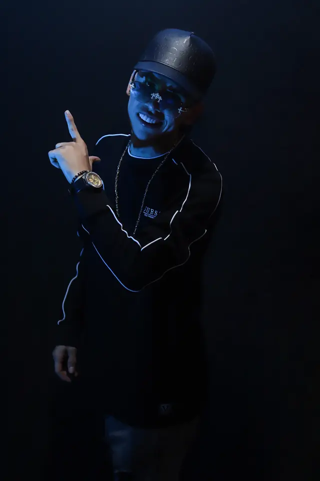 Artista iluminado con luz azul que señala hacia arriba, fondo negro