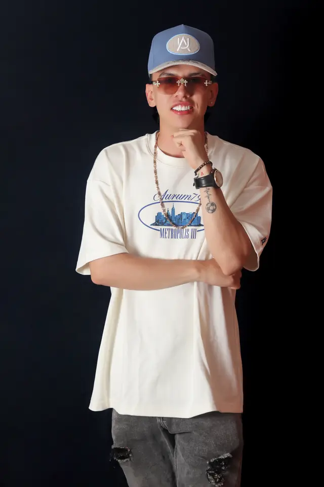 Retrato de estudio de un artista con gorra y camiseta clara sobre fondo negro
