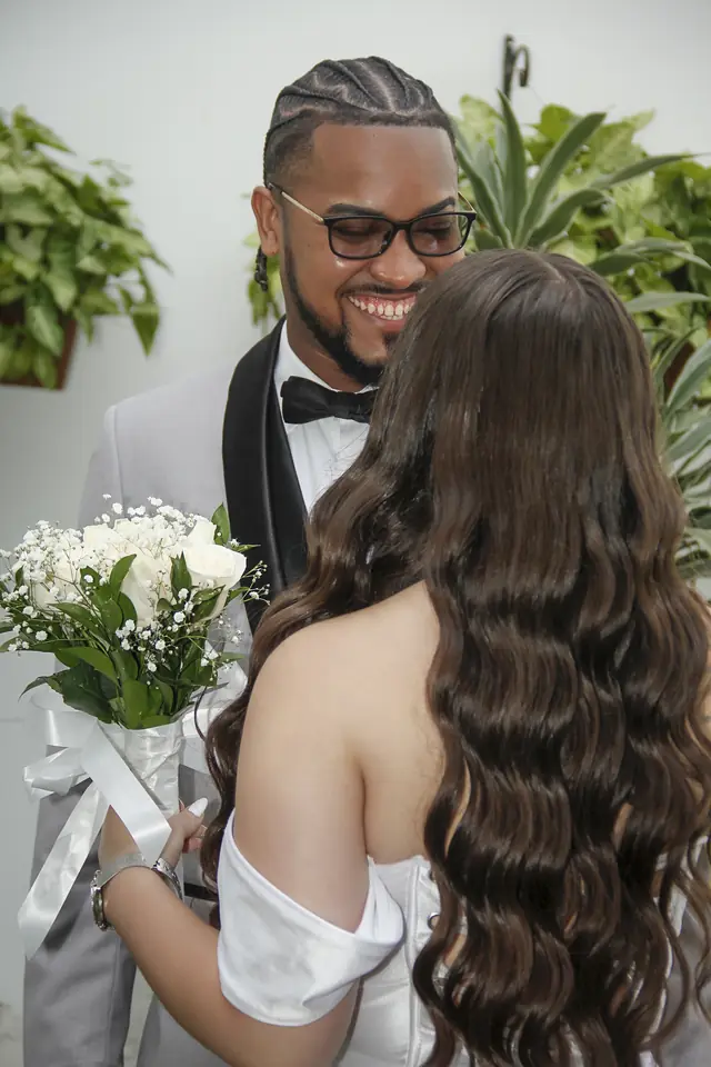 Novio sonriente que mira a la novia, ella de espaldas con el ramo