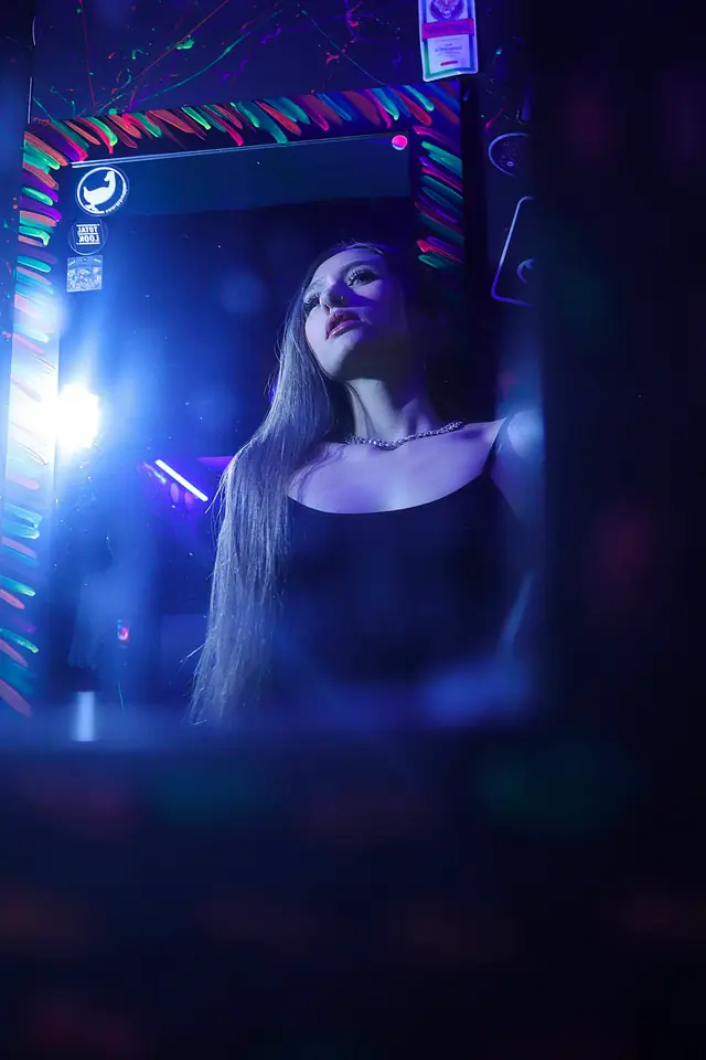 Mujer reflejada en un espejo dentro de un bar con luces de neón azules