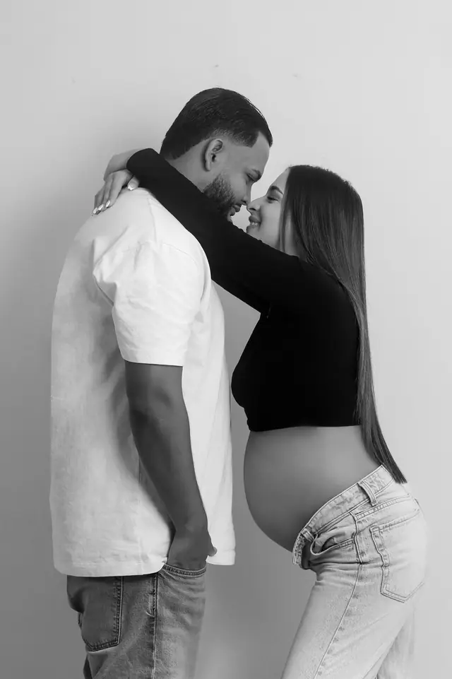 Pareja abrazada en una sesión de maternidad en estudio