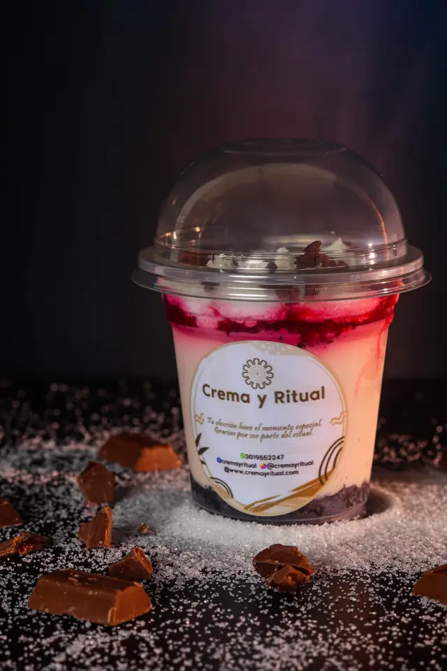 Postre de frutos rojos en vaso sobre azúcar espolvoreada y trozos de chocolate