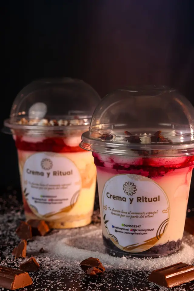 Dos postres de frutos rojos en vaso, uno delante del otro, sobre fondo oscuro